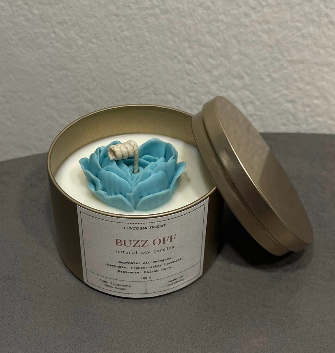 BUZZ OFF" Duftkerze aus natürlichem Sojawachs in goldener Metalldose mit blauer Wachsbume, Duftnoten von Zitronengras, französischem Lavendel und Balsamtanne.