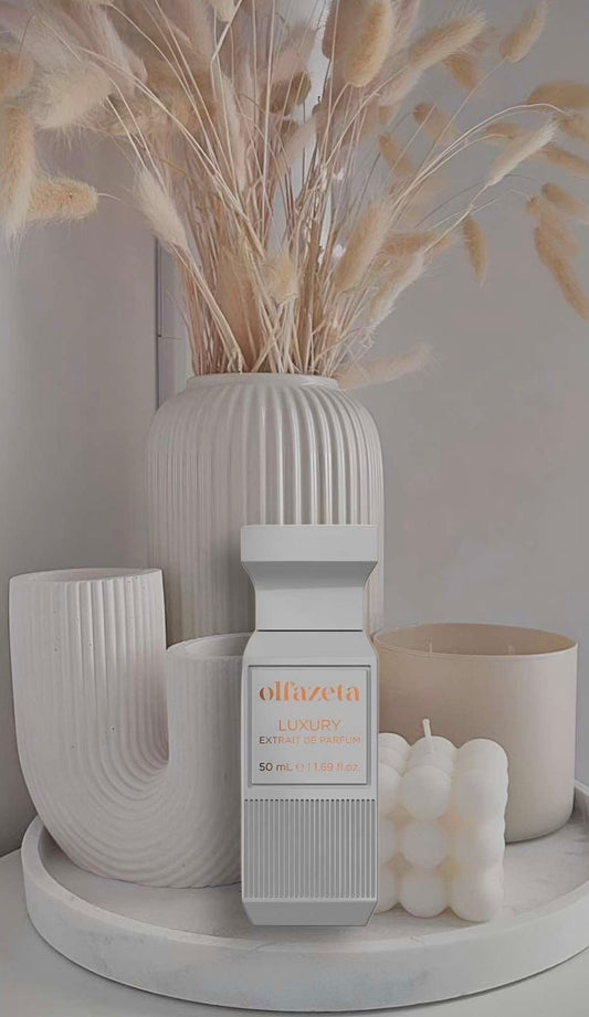 Unisex-Parfum in weißem Luxusflakon, stilvoll arrangiert vor minimalistischer Dekoration mit Kerzen und modernen Vasen in Beige- und Cremetönen