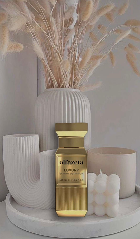 Unisex-Parfum von olfazeta in goldfarbenem Luxusflakon, stilvoll arrangiert vor minimalistischer Dekoration mit Kerzen und modernen Vasen in Beige- und Cremetönen