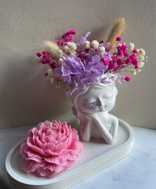 Minimalistische Betonvase mit Trockenblumen und Rosenkerze als stilvolle Wohnraumdekoration in Rosa und Fliederfarben